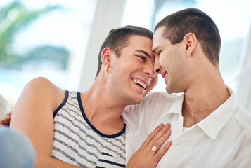 Fototapeta premium Laughing, gay and happy couple hug in home to relax for queer pride for homosexual, love or comfort. People, affection and men bonding with funny joke in apartment for relationship, marriage or rest