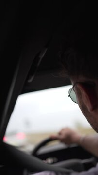 driver video, profile from behind, detail sunglasses and face, modern man in his late twenties relaxed driving on curvy coastal road