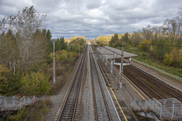 Fototapeta premium Railway station. The railway tracks pass through a small platform where people can board the carriages. A railway for transporting goods and transporting people.