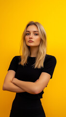 Obraz premium Blonde girl in black top and black leggings against yellow studio wall background