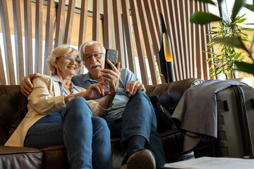 Mature couple sitting at the hall of hotel and wait for room key after registration in hotel for vacation