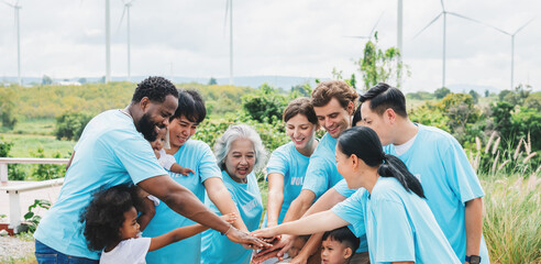 group of people in blue shirts are holding hands in a circle
