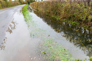 A drainage ditch overflowing after heavy rain in a lane near the village of Clanfield, Oxfordshire,...