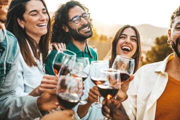 Happy friends toast with red wine at a vineyard - Group of young people enjoying happy hour at rooftop winery bar - Gathering and beverage life style concept