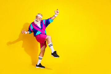 Full length photo of handsome good mood senior guy oldschool sportswear having fun emtpy space isolated yellow color background