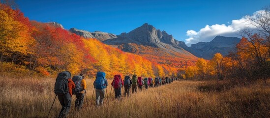 A group of hikers traversing a colorful autumn landscape with mountains in the background.