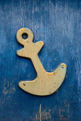 Yellow wooden anchor on blue wooden wall