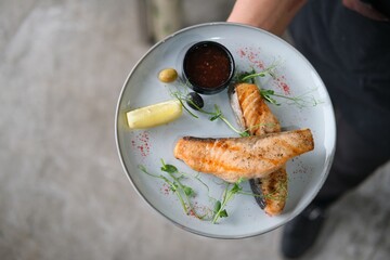 Chef Garnishing Grilled Fish with Herbs