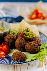 Falafel plate with hummus, cherry tomatoes, lettuce, and pita chips, perfect Mediterranean meal