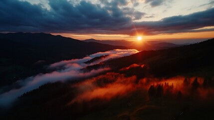 Aerial view of a beautiful sunset over a mountain range with clouds and fog.