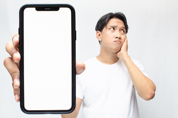 an overthinker young asian man thinking deeply while showing his big screen phone after receiving...