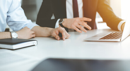 Unknown business people using laptop computer at the desk in modern office. Businessman or male entrepreneur is working with his colleague. Teamwork and partnership concept