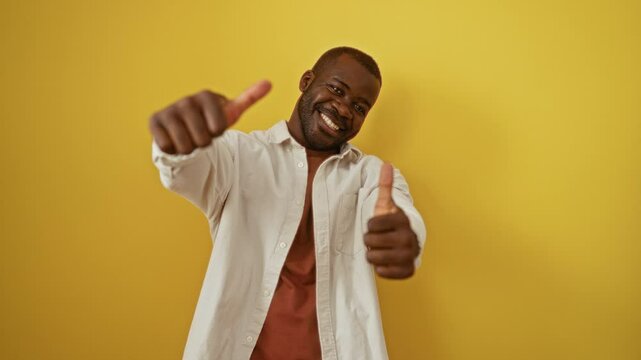 Thumbs up from african american man wearing shirt, happy smiling success gesture, positive winner over isolated yellow background