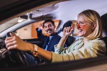 Happy energetic couple drives around in the car. They smile and sing.