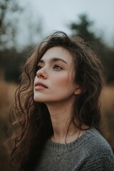Fototapeta premium A woman with wavy brown hair gazing into the distance outdoors.