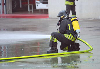 firefighter in action with oxygen tank and respirator spraying extinguishing agent during an emergency