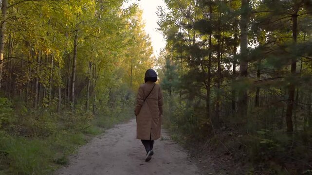 a girl in a raincoat walks along the road through