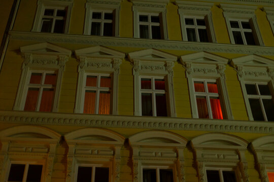 A tall building that features numerous windows is brightly lit up during the night, showcasing its beautiful facade and architecture