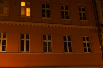 Obraz premium A tall and modern building, adorned with numerous large windows, is beautifully illuminated and glowing at night, creating a stunning sight
