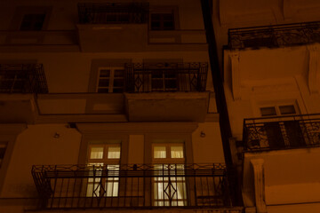 A beautifully designed building with an elegant balcony is brightly lit up during the nighttime, creating a stunning visual display
