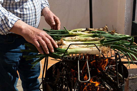Hombre asando cal&ccedil;ots en barbacoa.