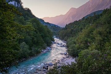 Vibrant river winds through a lush, green valley, surrounded by towering mountains