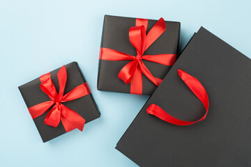 Black shopping bag and gift boxes on color background, top view.Black Friday concept