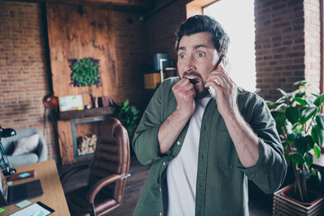 Photo of attractive young man scared amazed talk phone wear green shirt comfortable modern office...