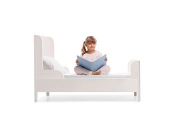 Kid in pajamas sitting in a bed with a book