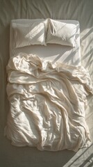 Obraz premium A cozy, unmade bed with wrinkled white sheets and sunlight streaming in the morning