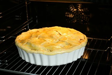 Baking dish with raw homemade apple pie in oven, closeup