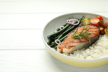 Tasty grilled salmon steak with rice and vegetables on white wooden table, closeup. Space for text