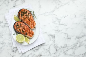 Tasty grilled salmon steaks with thyme, dill and lime on white marble table, top view. Space for...