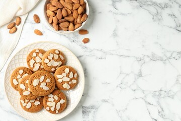 Tasty cookies with almond flakes and nuts on white marble table, top view. Space for text