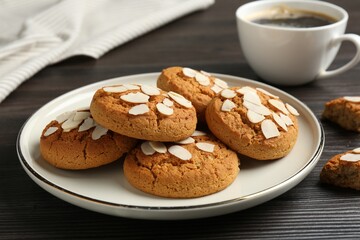 Tasty cookies with almond flakes and coffee on wooden table, closeup