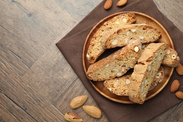 Traditional Italian almond biscuits (Cantucci) and nuts on wooden table, top view. Space for text
