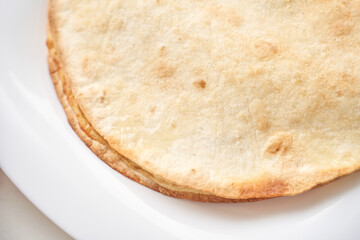Close-up of freshly baked flatbread on white plate.