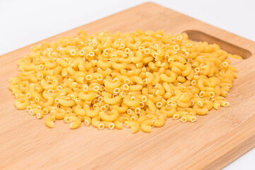 A Heap of Uncooked Chifferi Rigati Pasta on Wooden Kitchen Board. Fat and Unhealthy Food. Classic Dry Macaroni. Italian Culture and Cuisine. Raw Pasta