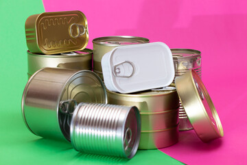 A Group of Stacked Tin Cans on Split Green and Cyan Background. Canned Food. Aluminum Cans for Safe and Long Term Storage of Food. Steel Sealed Food Storage Containers
