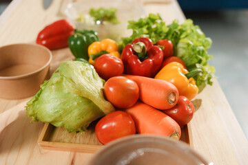 Fresh vegetables are sitting on a wooden cutting board, ready for a salad to be prepared