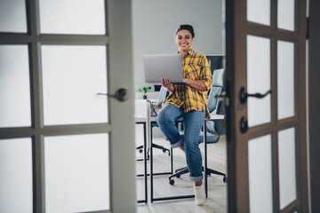 Full body photo of young woman sit table work netbook wear yellow plaid shirt comfortable modern office room interior indoors workspace