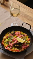 Seafood Paella with Shells and Lemon in Pan with Wine Glass