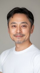 Fototapeta premium 中立的な背景に対して白い T シャツを着て微笑んでいる自信に満ちた中年男性