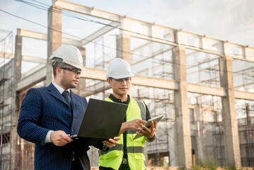 Two construction engineers inspect the building structure and the progress of the construction plan