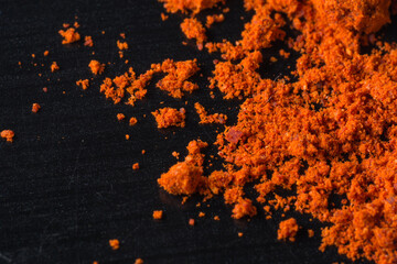 Vibrant orange powder scattered on a dark textured surface.