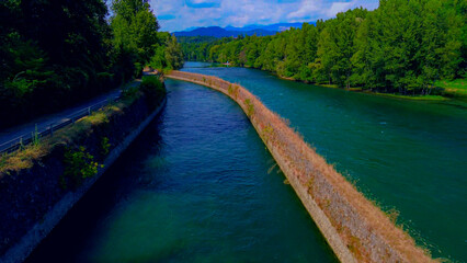 Trezzo sul Adda, Italy. Aerial view of a mountain freshwater river with low water level surrounded by green trees. White swans on the river. Forest. Hydroelectric power station. Green planet. Ecology
