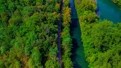 Trezzo sul Adda, Italy. Aerial view of a mountain freshwater river with low water level surrounded by green trees. White swans on the river. Forest. Hydroelectric power station. Green planet. Ecology
