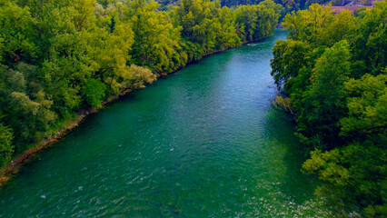 Trezzo sul Adda, Italy. Aerial view of a mountain freshwater river with low water level surrounded by green trees. White swans on the river. Forest. Hydroelectric power station. Green planet. Ecology