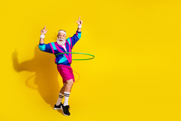 Full length photo of funny aged sportsman hula hoop empty space retro uniform isolated on yellow...