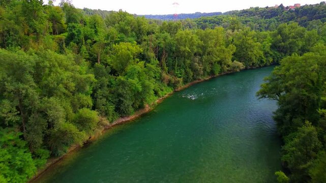 Trezzo sul Adda, Italy. Aerial view of a mountain freshwater river with low water level surrounded by green trees. White swans on the river. Forest. Hydroelectric power station. Green planet. Ecology